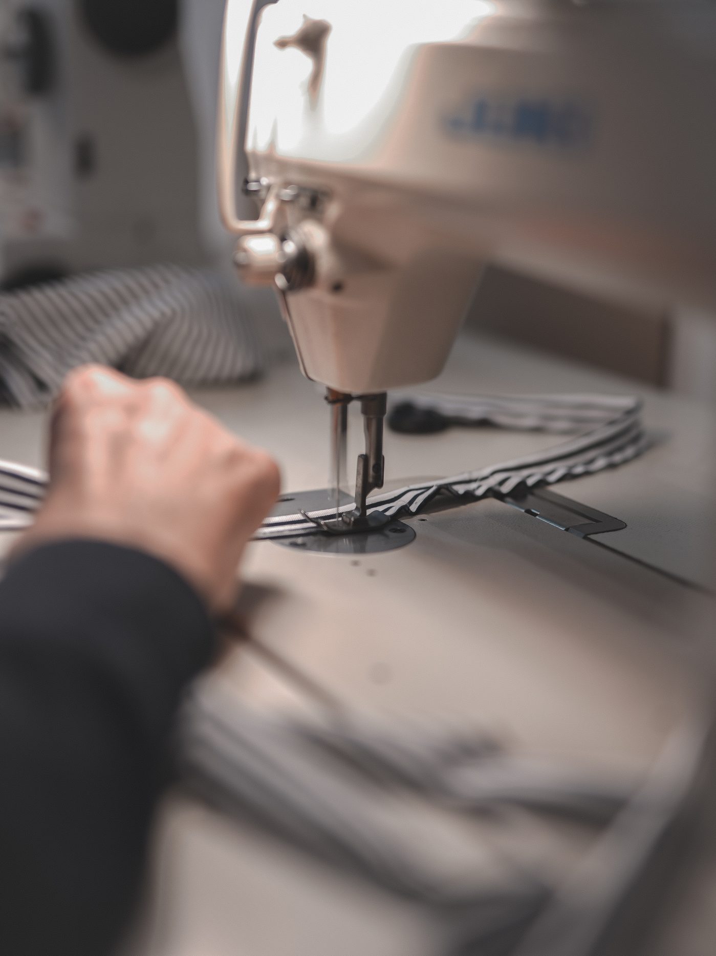 Eine Hand näht ein gestreiftes Stück an der Nähmaschine